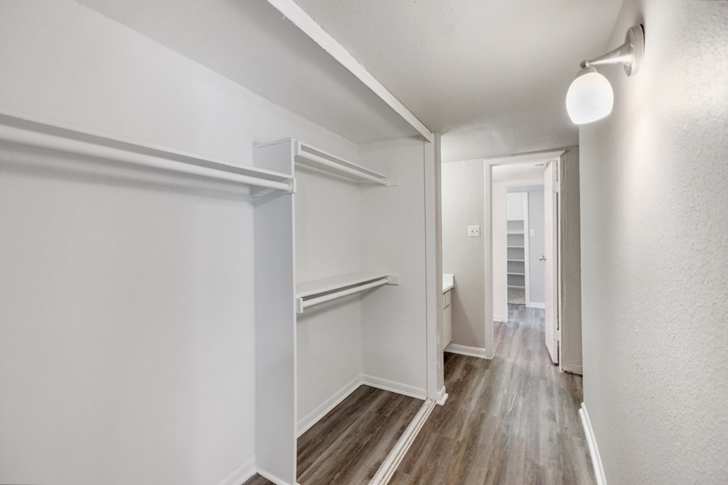an empty room with white walls and wood floors and a hallway with a white door