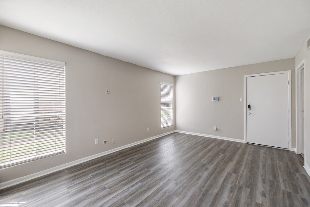 an empty living room with wood floors and a white door