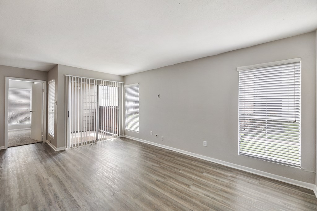 the living room of an apartment with wood flooring and a balcony