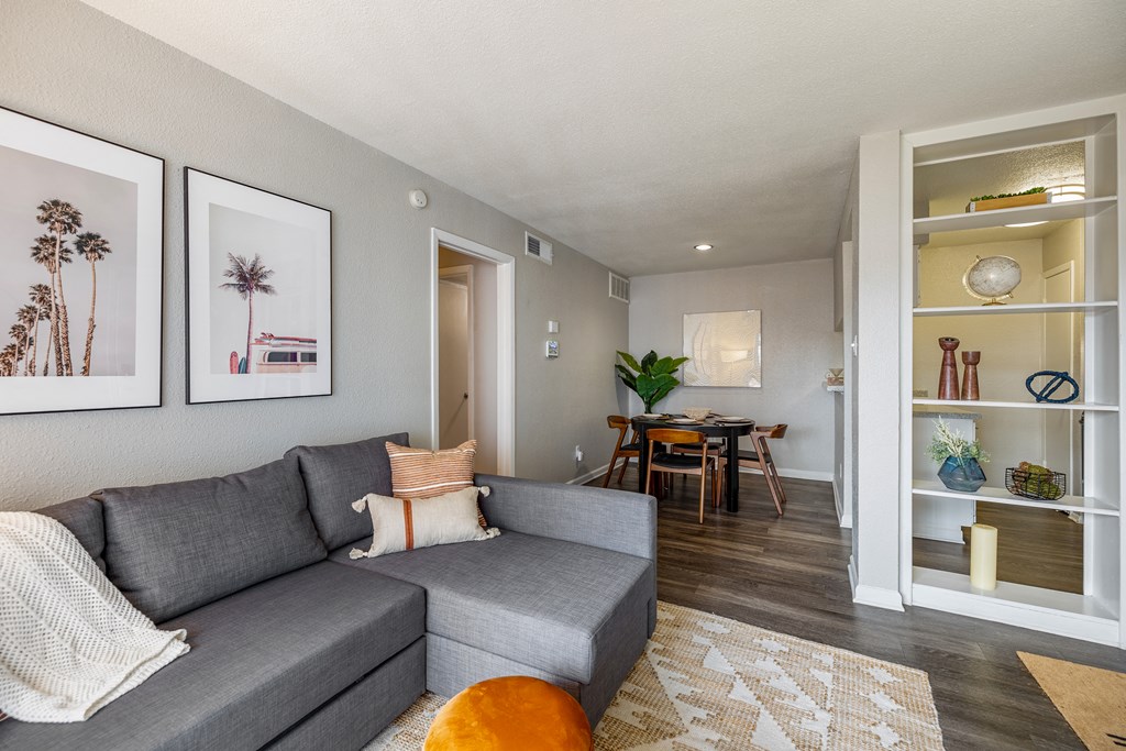 a living room with a gray couch and a dining room