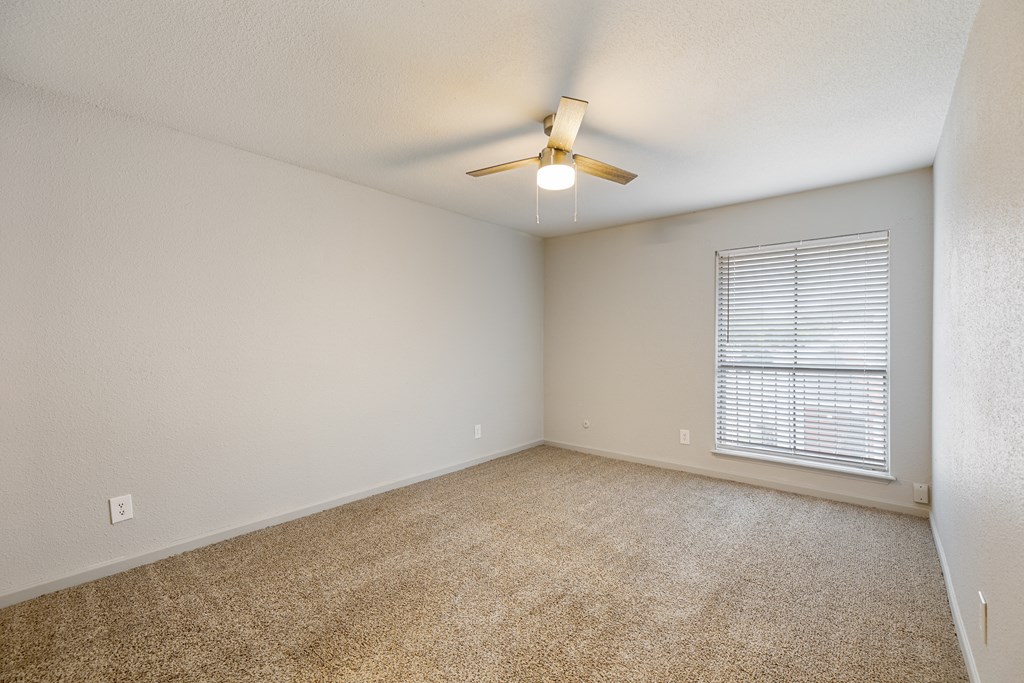 an empty living room with a ceiling fan and a window