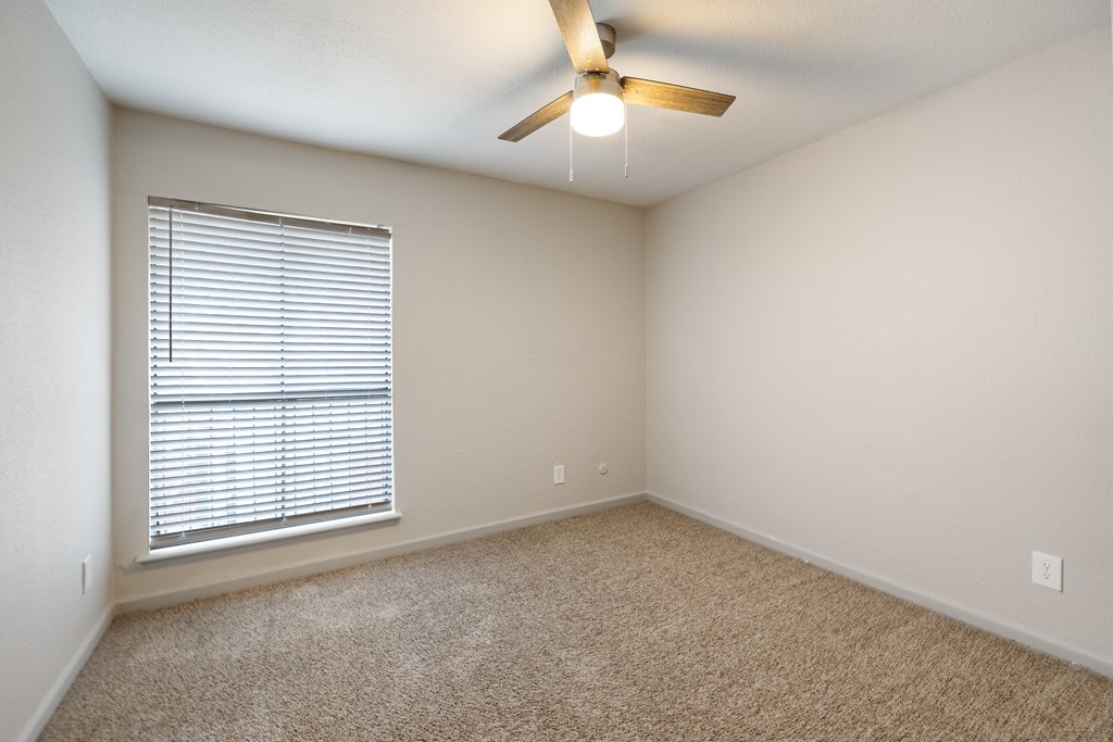 an empty room with a large window and a ceiling fan