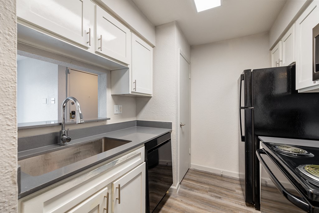 a kitchen with white cabinets and a sink and a refrigerator