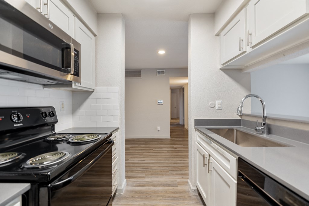 a kitchen with white cabinets and black appliances and a sink