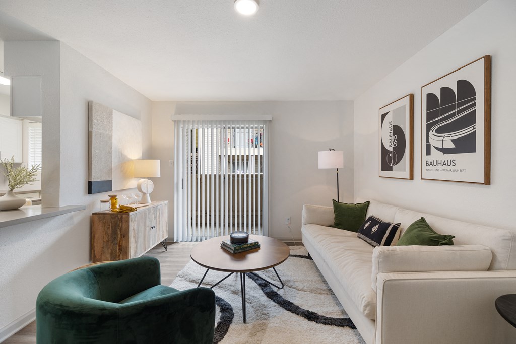 a living room with a white couch and green chairs