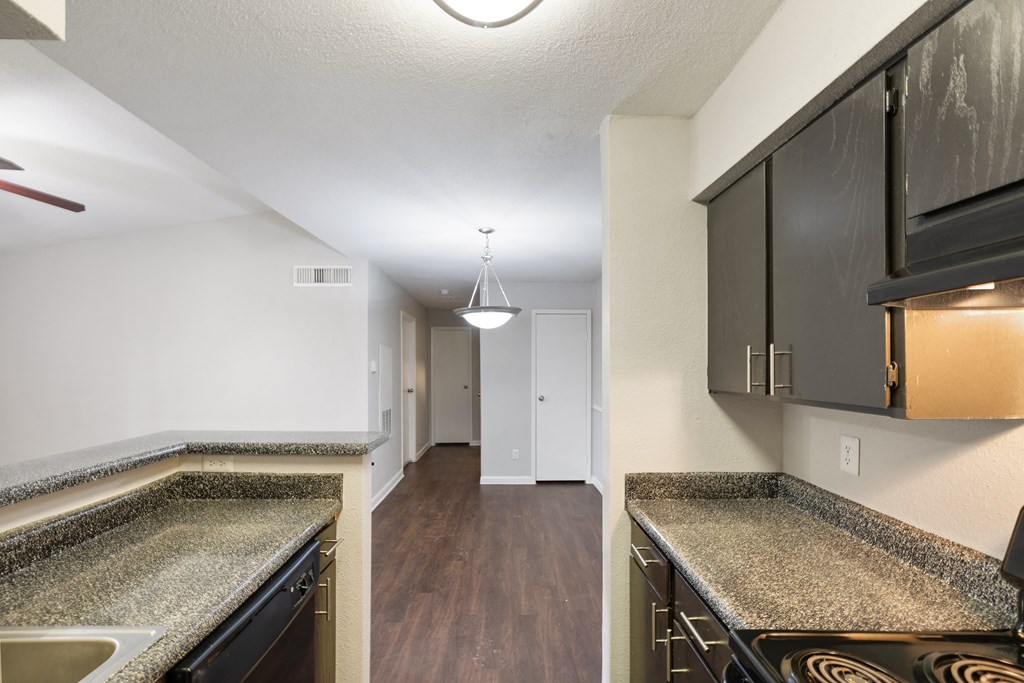 an empty kitchen with granite counter tops and dark cabinets