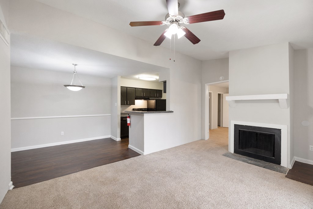 an empty living room with a fireplace and a ceiling fan