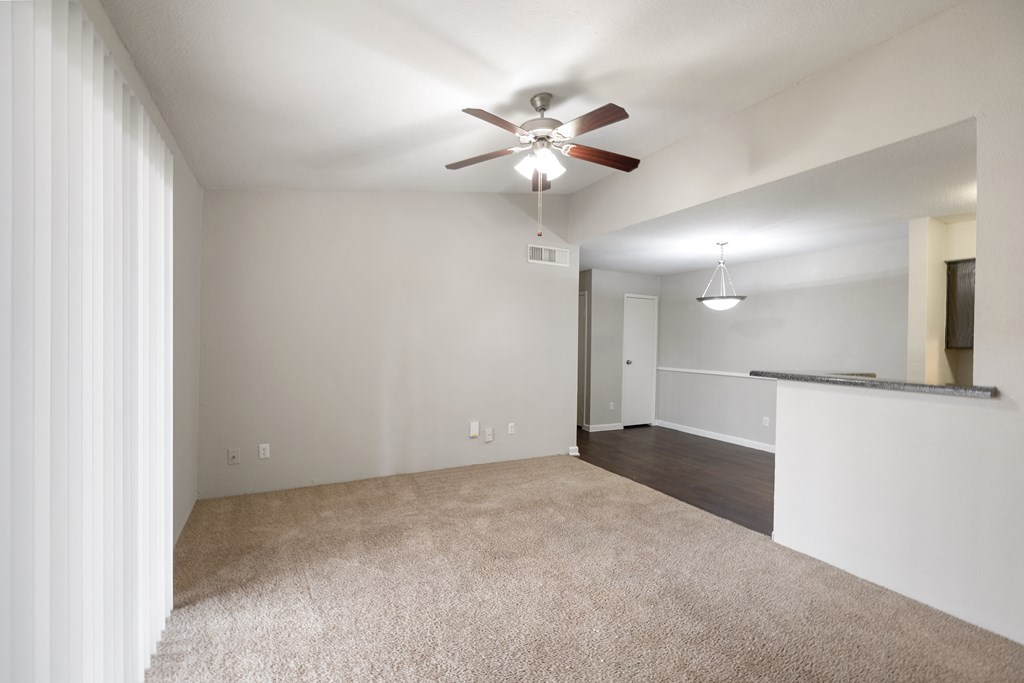 an empty living room with carpet and a ceiling fan
