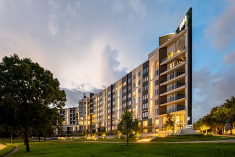 A modern apartment building with a green lawn in front.