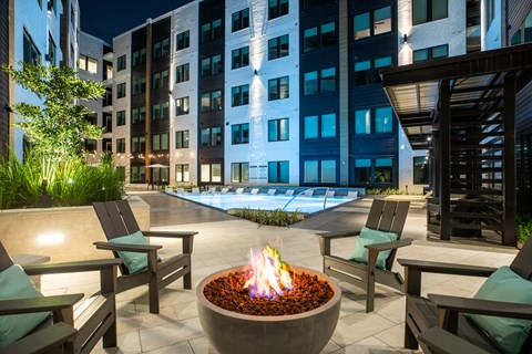 A fire pit sits in the middle of a patio surrounded by chairs.