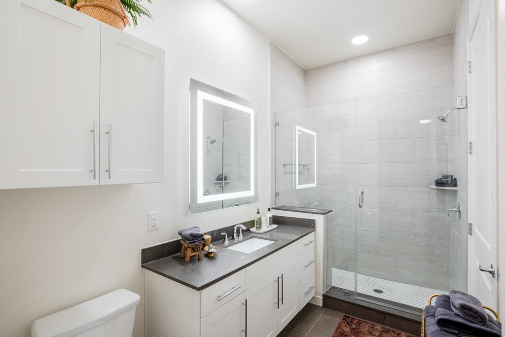 a bathroom with white cabinets and a shower and a sink