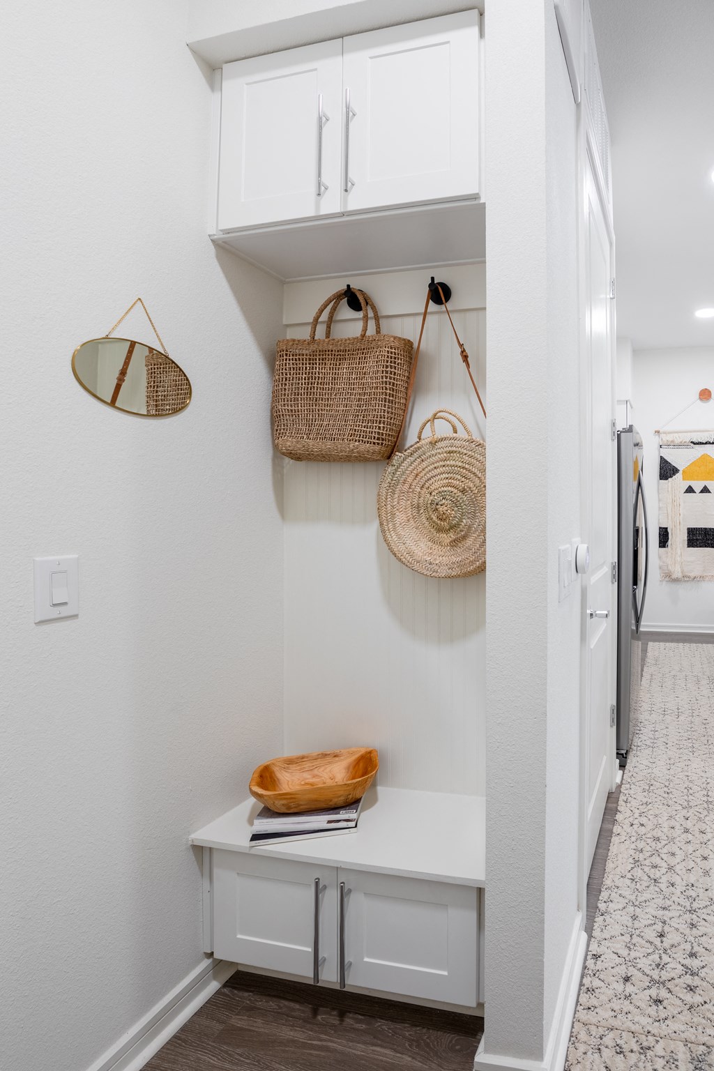a laundry room with white cabinets and baskets on the wall