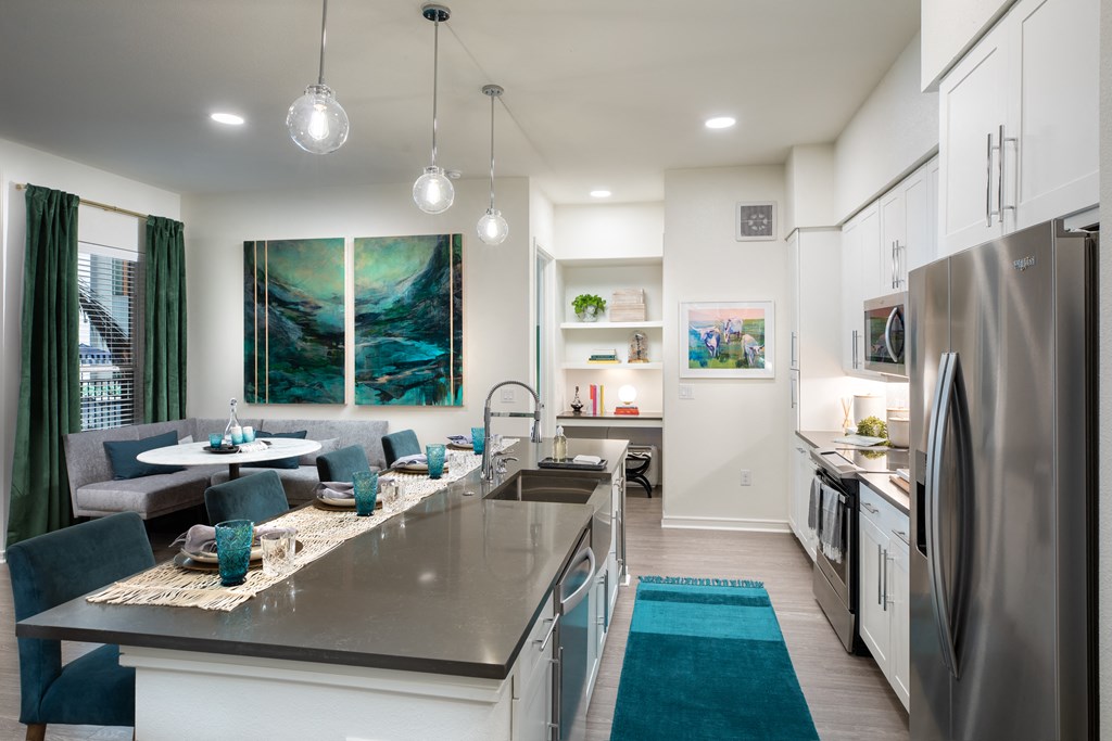 an open kitchen and living room with a large island and stainless steel appliances