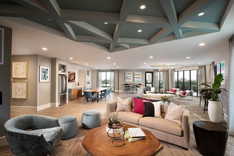 A modern living room with a grey sofa, a grey armchair, a wooden coffee table, and a large window with a view of the city.