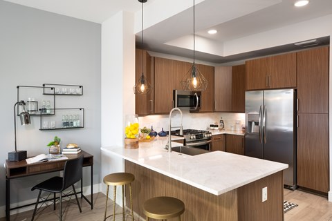A modern kitchen with a white countertop and wooden cabinets.