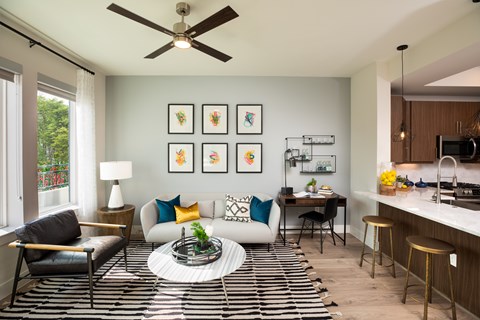 A living room with a black and white striped rug and a ceiling fan.