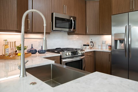 A modern kitchen with a stainless steel sink and refrigerator.