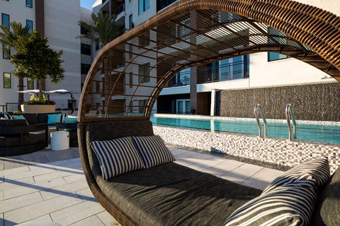 A wooden outdoor sofa with a striped cushion sits on a patio.