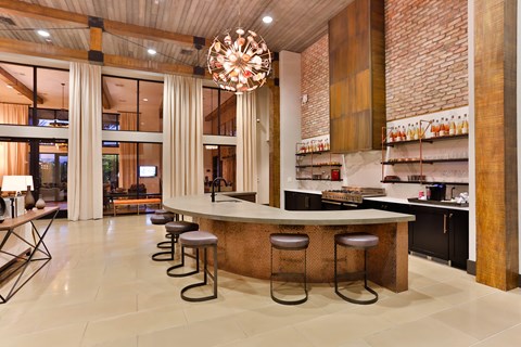 A modern kitchen with a long bar and stools.
