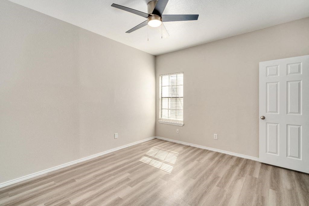 an empty living room with a ceiling fan and a window