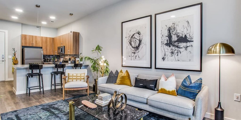 A living room with a grey couch, a black coffee table, and a bar area with stools.