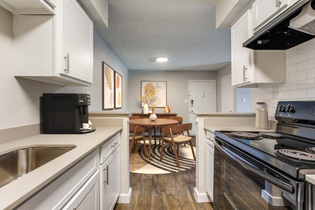 an open kitchen and dining room with white cabinets and appliances and a table and chairs