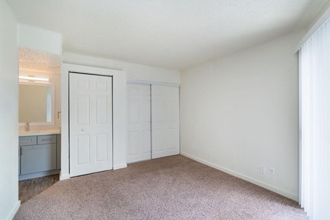 a bedroom with white walls and carpet and a door to a bathroom