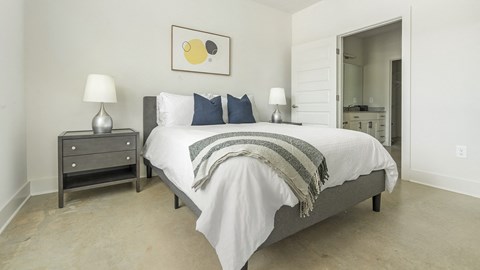 A bedroom with a bed, nightstand, and lamp.