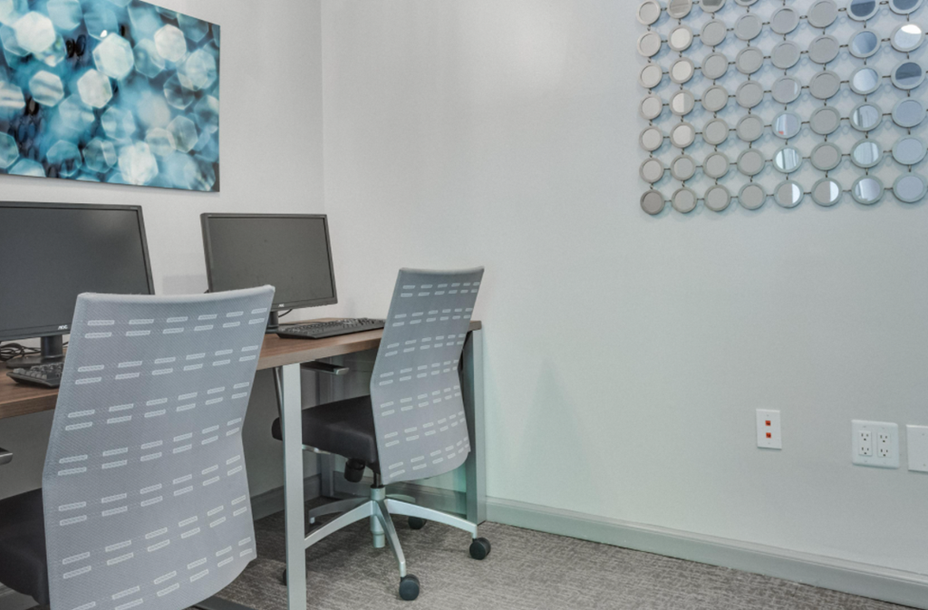 a desk with two computer monitors and two chairs
