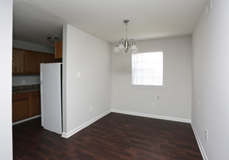 an empty living room with a refrigerator in the corner