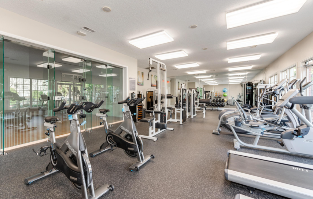 a large fitness room with cardio equipment and windows
