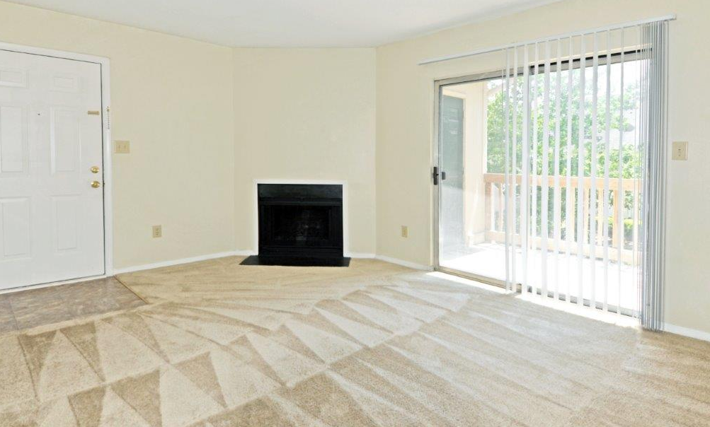 an empty living room with a fireplace and a sliding glass door