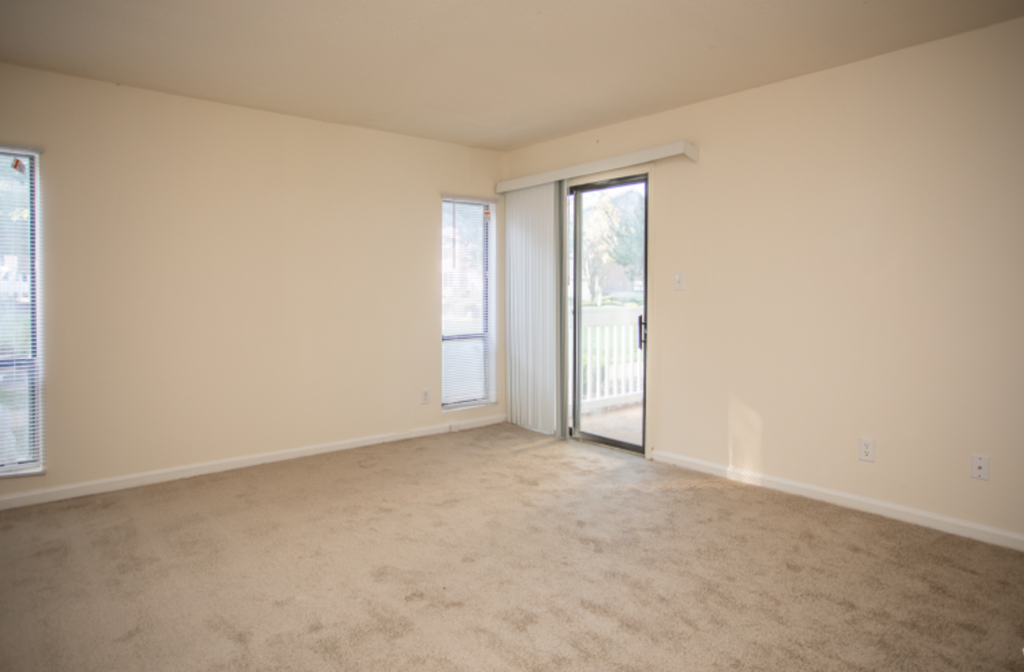 an empty living room with a door to a balcony
