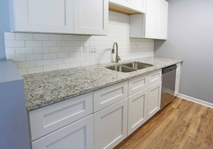 an empty kitchen with white cabinets and a sink