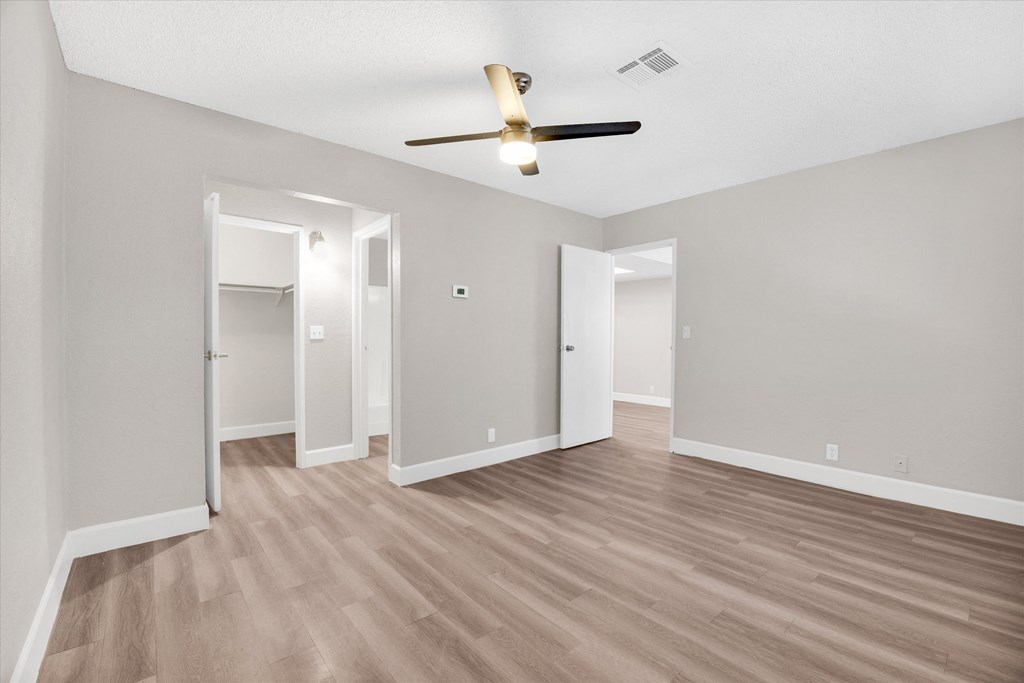 an empty living room with a ceiling fan and hardwood floors