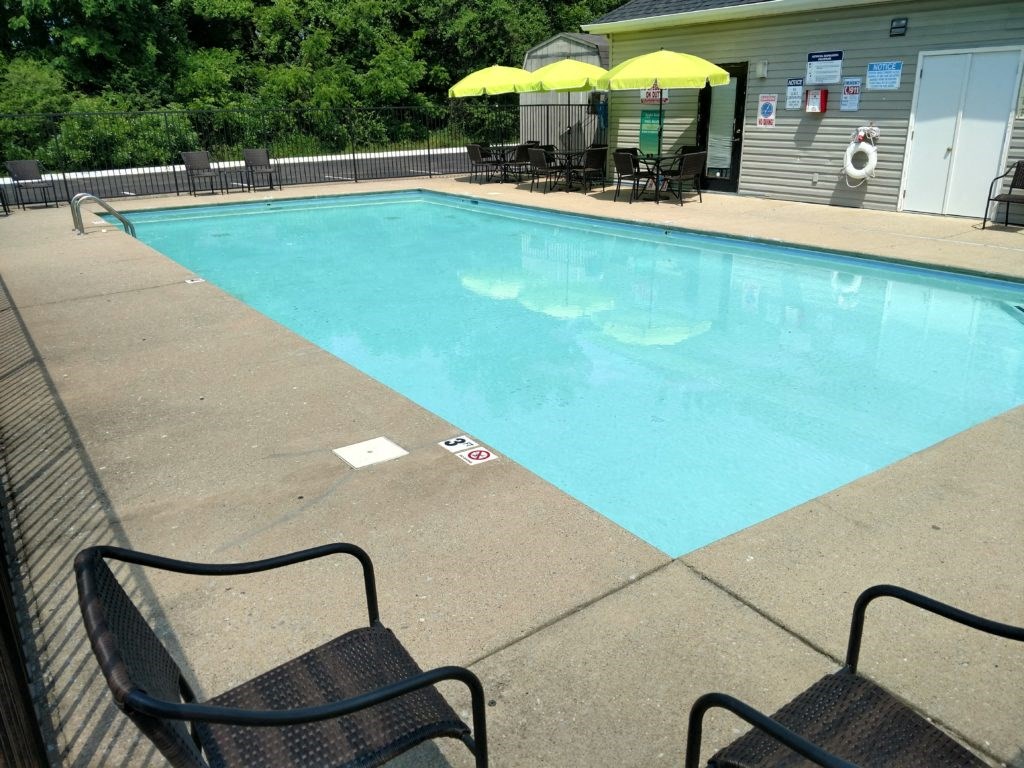 a swimming pool with two chairs and two umbrellas