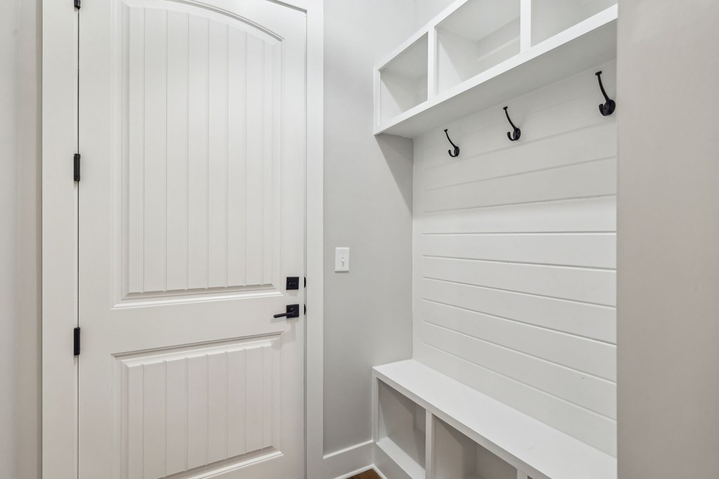 A white closet with a bench and hooks.