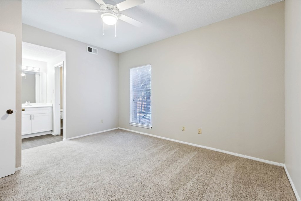 A room with a ceiling fan and carpeted floor.