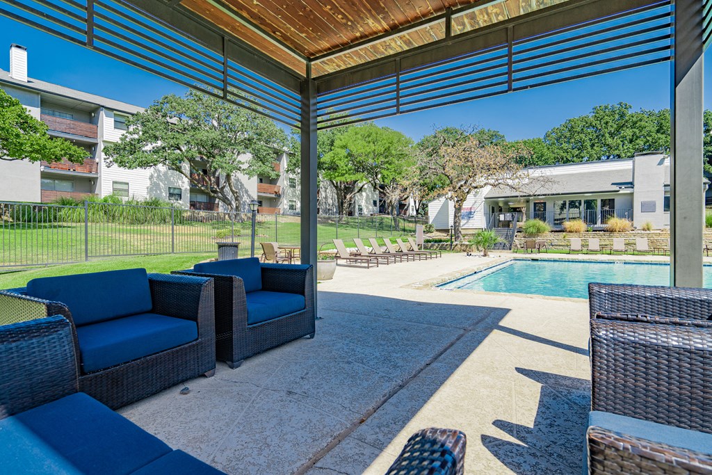 a covered patio with blue chairs and a pool