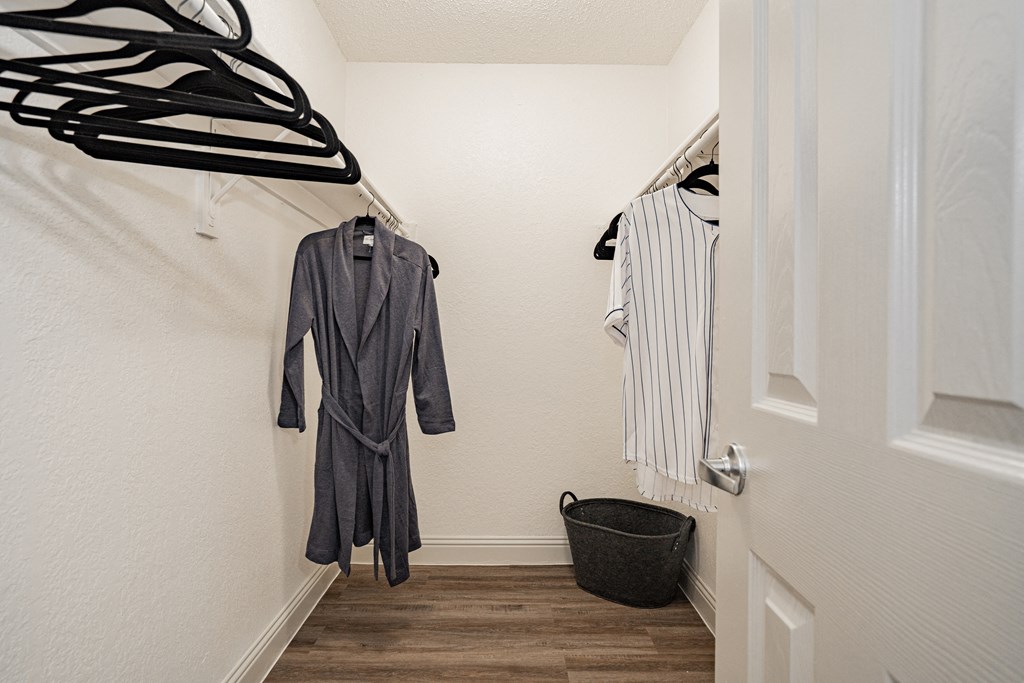 a walk in closet with clothes hanging on the wall