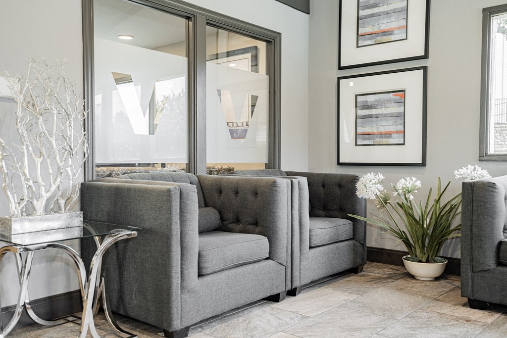 a living room with gray couches and a glass table