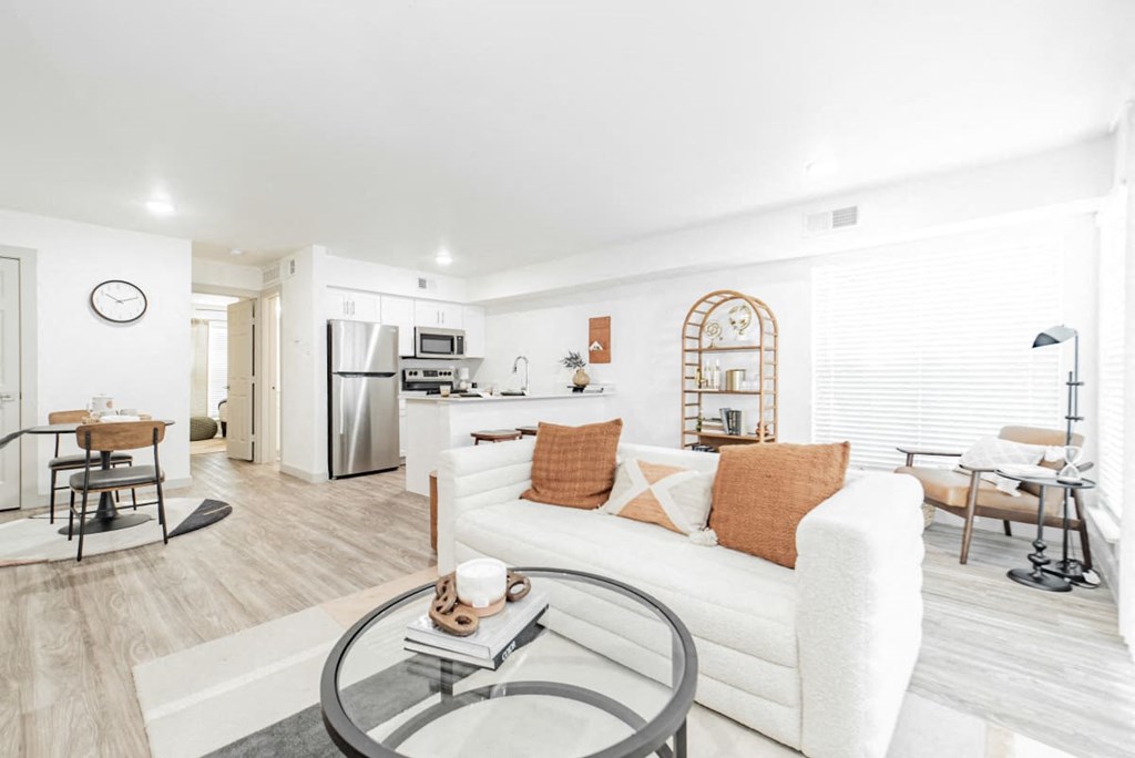 A modern living room with a white couch and a glass coffee table.