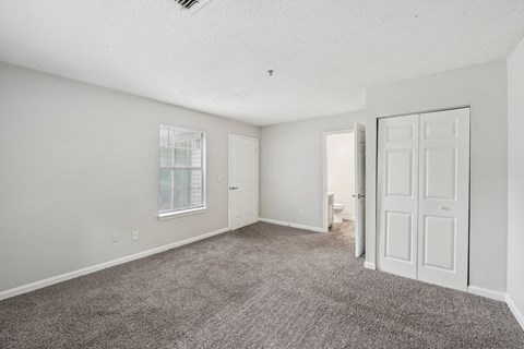 A spacious room with a carpeted floor and white walls.