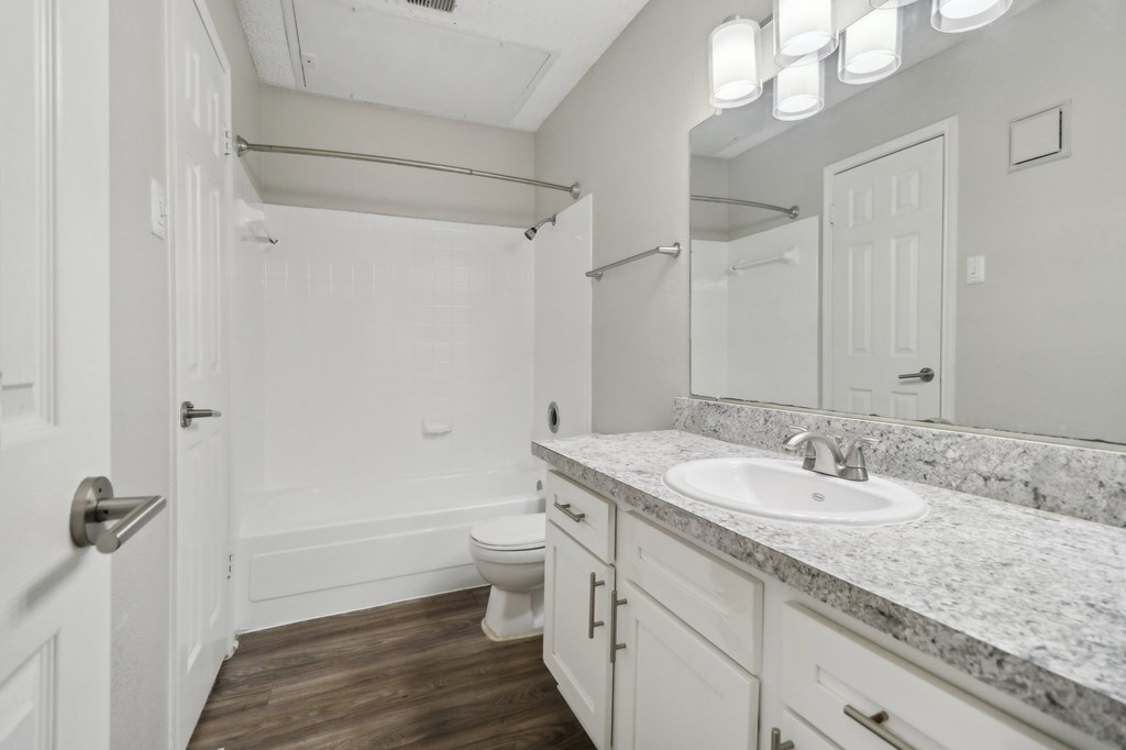 A bathroom with a white door, sink, and toilet.