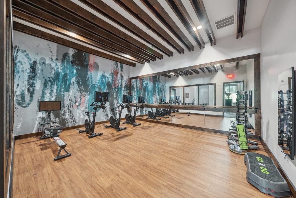 a gym with weights and cardio equipment and a mural on the wall