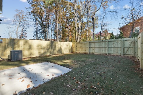 A backyard with a fence and a tree.