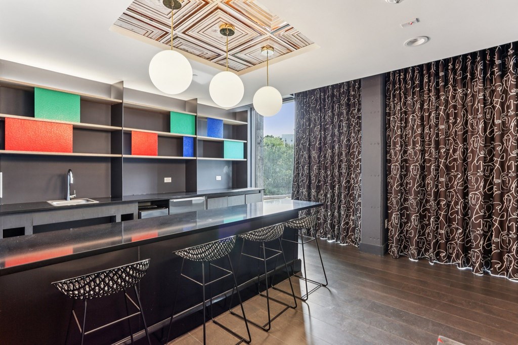 A modern kitchen with a black countertop and bar stools.
