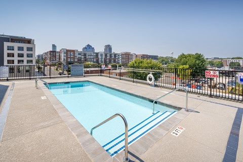 a pool on the roof of a building with a city in the background