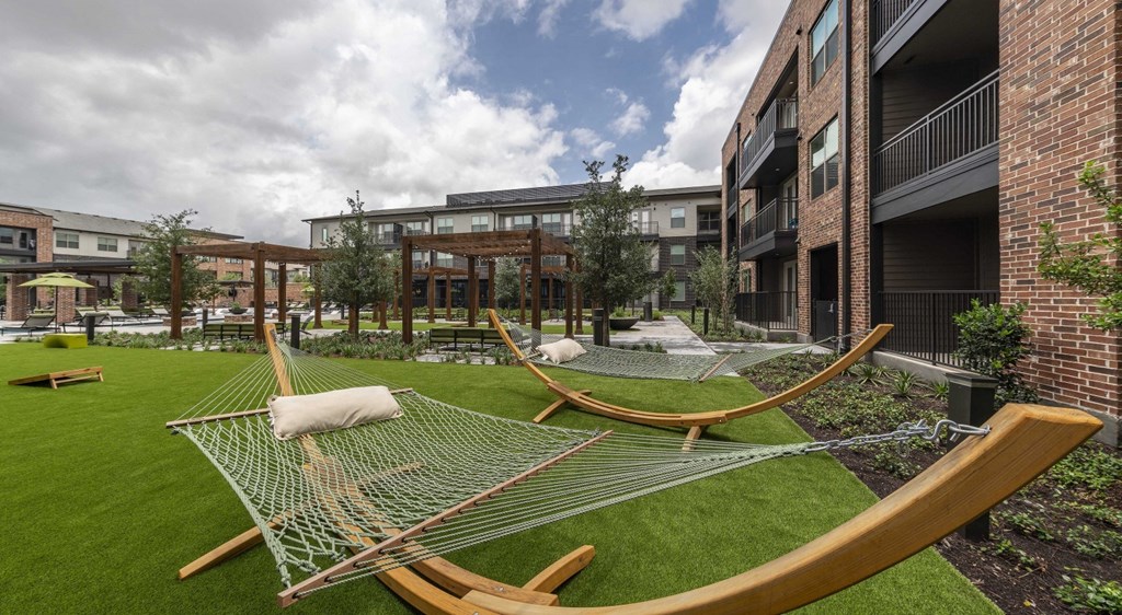 a courtyard with hammocks and buildings on a cloudy day