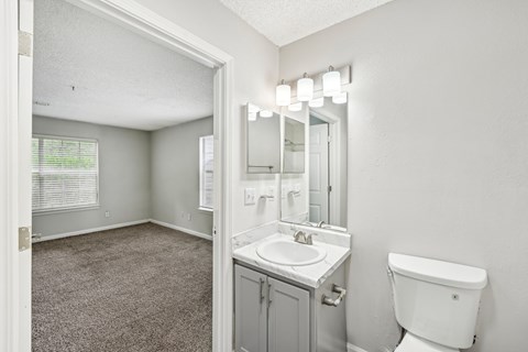A white bathroom with a sink, toilet, and mirror.